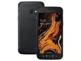 A person holding the Samsung Galaxy Xcover 4s in one hand while hiking through rugged terrain.