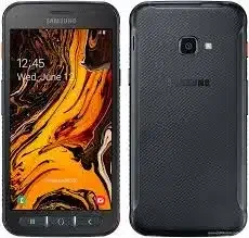 A person holding the Samsung Galaxy Xcover 4s in one hand while hiking through rugged terrain.