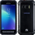 A rugged smartphone, Samsung Galaxy Xcover FieldPro, held in hand against a rocky background.